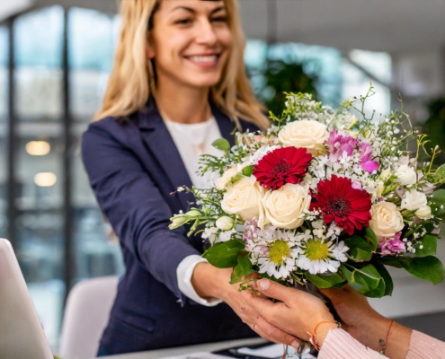 Verschiedene frische Blumensträuße auf einem Bürotisch als Zeichen der Anerkennung für Mitarbeiter